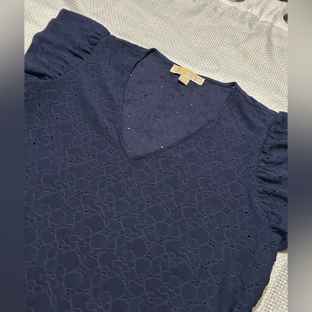 This item is a Michael Kors navy blue eyelet ruffled flutter sleeve top.